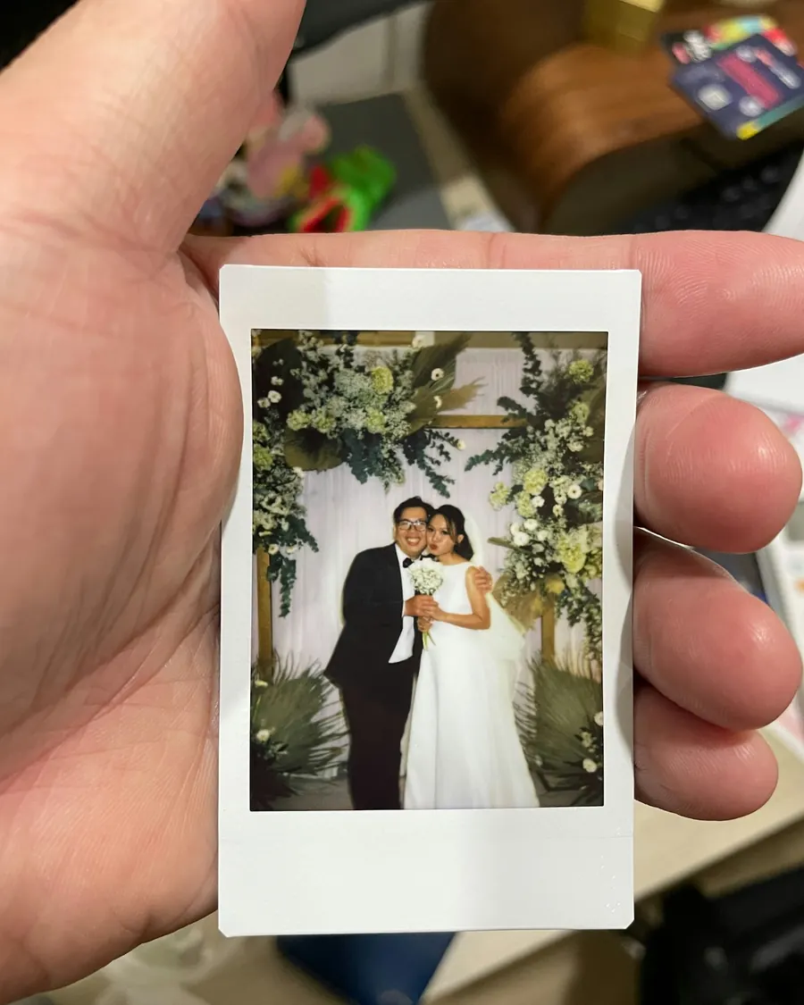 Mão segurando a foto impressa dos noivos durante a festa de casamento